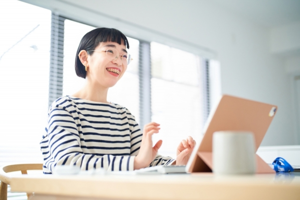 タブレットに向かって笑顔を向けている女性。中国語オンラインレッスンで学べば楽しみながら語学力が向上する。