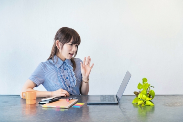 ノートパソコンに向かって手ぶりで話をしている女性。中国語オンラインレッスンで頑張って話そうとしている。