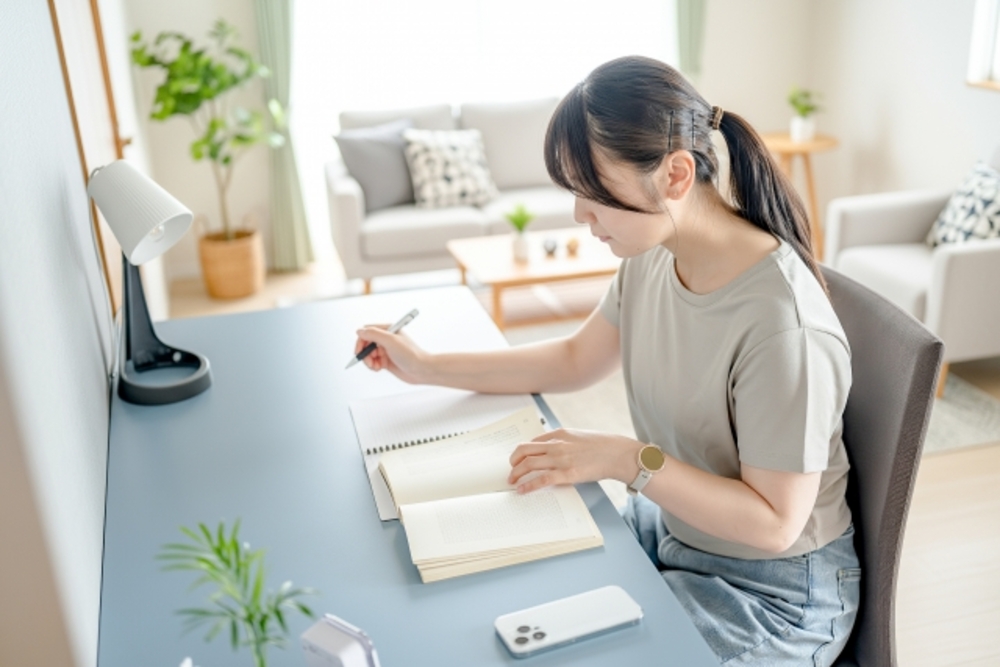 ノートに書き込みながら中国語を勉強する女性。春節と中国語学習の価値には関係はない。