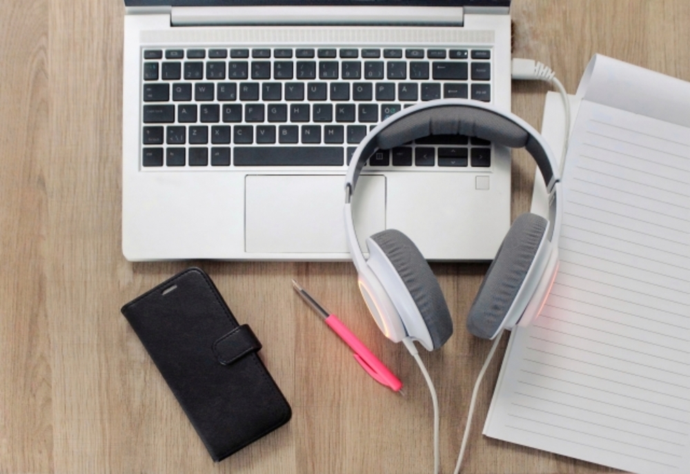 机の上に並べられたノートパソコン、スマホ、ペン、ヘッドホン、ノート。学習体制を整えれば独学でも中国語を習得できる。