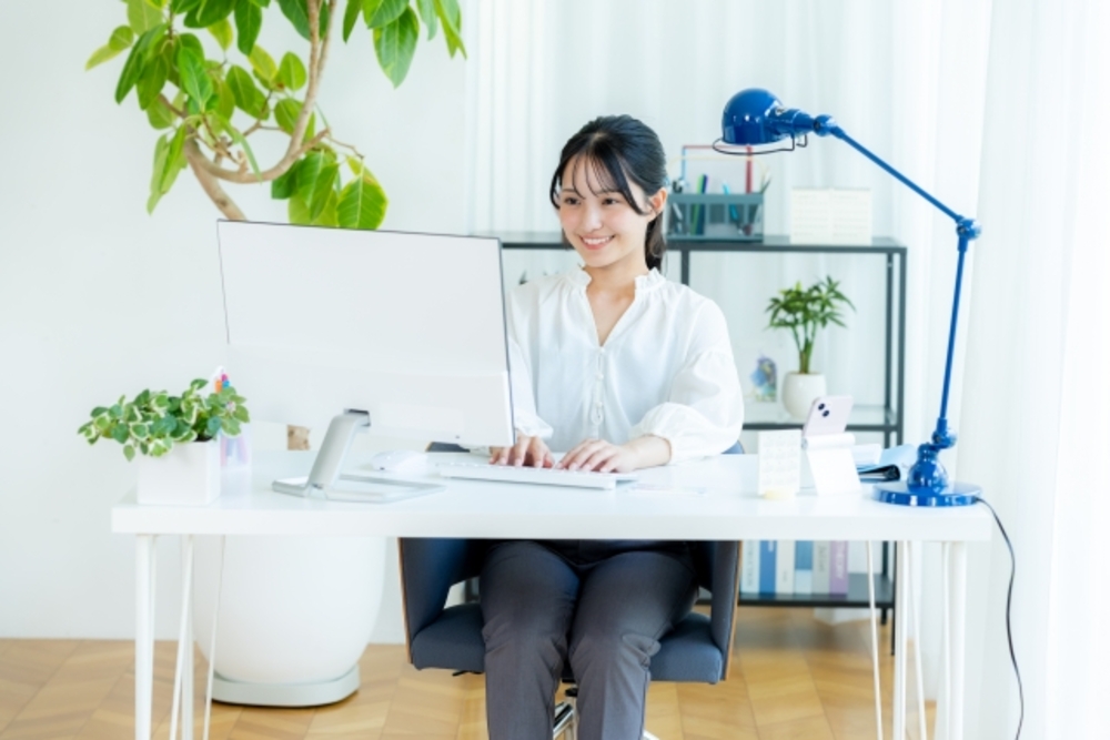 笑顔でオフィスのパソコンに向かう女性。簡体字と繁体字を上手く使い分ければビジネスの成功にもつながる。
