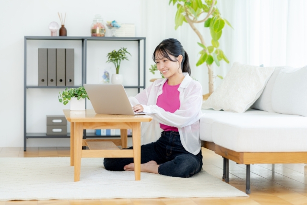 自宅でノートパソコンに向かう笑顔の女性。中国語を独学で学ぶ方法を考える。