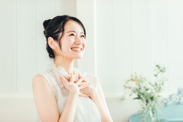 胸を押さえてほほ笑む女性。感動したことを「エモい」と表現する。