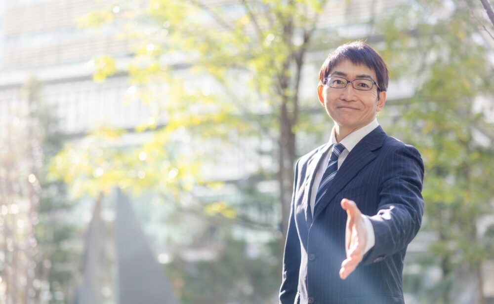 握手を求めるスーツ姿の男性。中国語で挨拶をする方法を学ぶ。