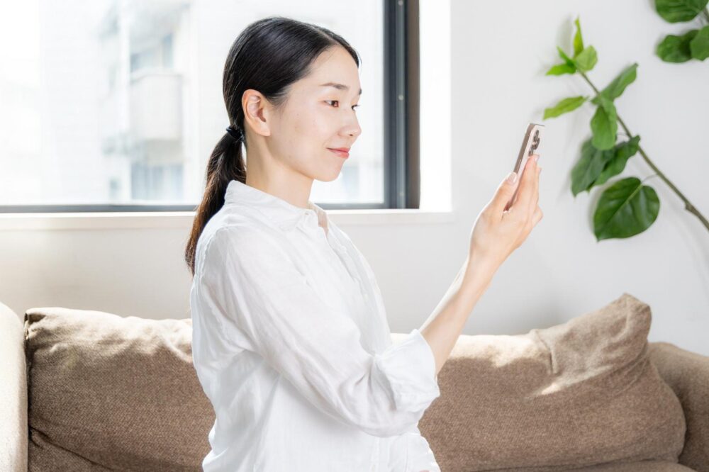 スマホを見る女性の横顔を写す。画面上の文字が簡体字か繁体字かによって親しみの感じ方が違う。