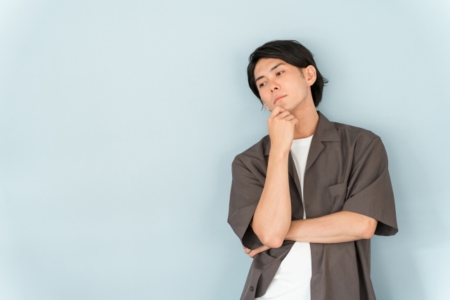 顎に手を当てて微妙な表情をする男性。中国語でかっこいいと言われても嬉しくない場面について考える。