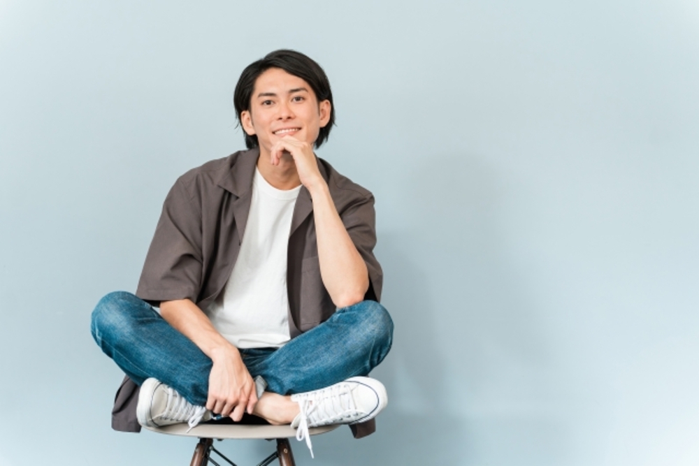 顎に手を当ててあぐらをかいて座る男性。中国語でかっこいいという表現を学ぶ。